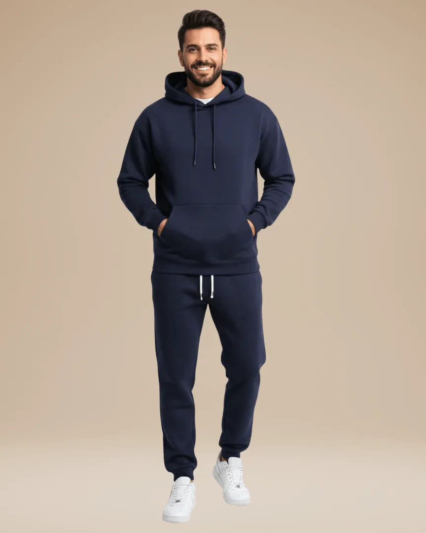 Man wearing a navy hoodie and matching joggers with white trainers, front view