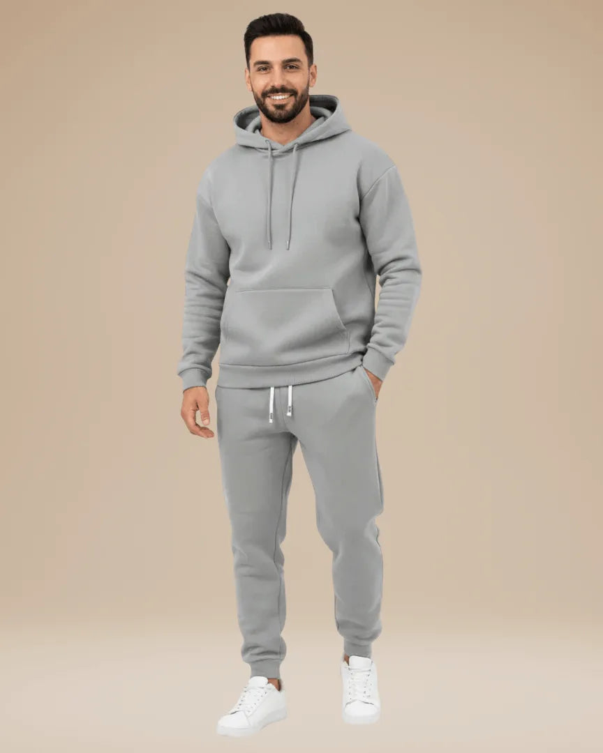 Man modelling a light grey hoodie and jogger tracksuit, front view with hands in pockets