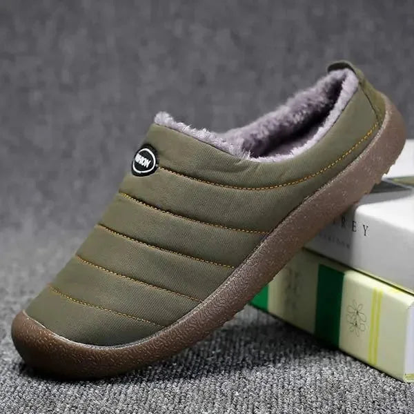 Three-quarter angle of a single green quilted mule slipper propped against a book stack