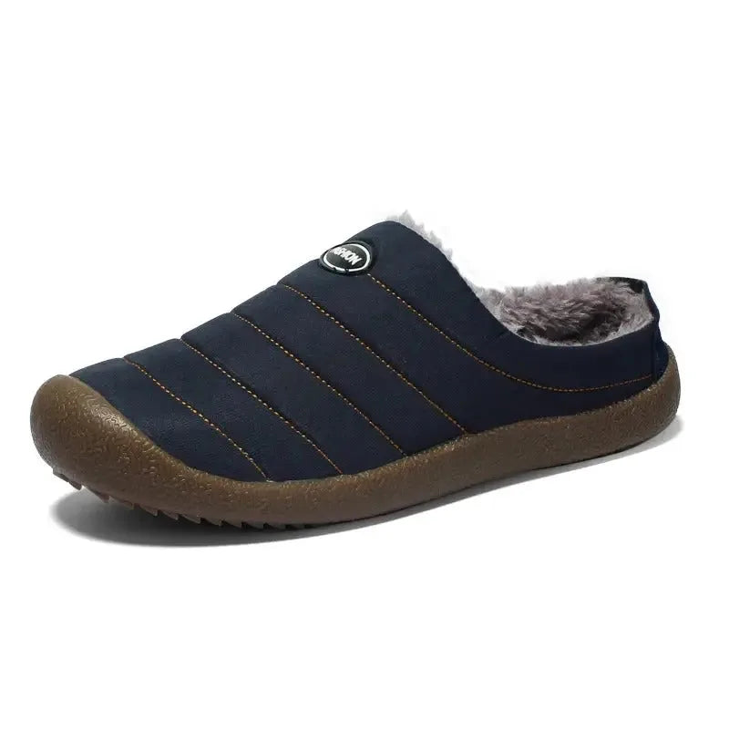 Side profile of a navy blue quilted slip-on slipper showing the soft grey fleece collar
