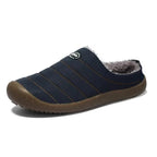 Side profile of a navy blue quilted slip-on slipper showing the soft grey fleece collar