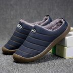 Pair of navy blue fleece-lined slip-on slippers placed on a textured grey rug near books