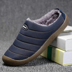 Hand holding a navy blue quilted slipper to show its padded stitched panels and grip sole