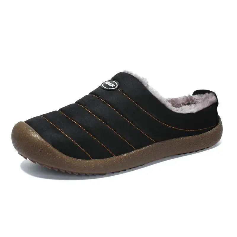 Side view of a navy quilted slipper resting against stacked books on a grey rug