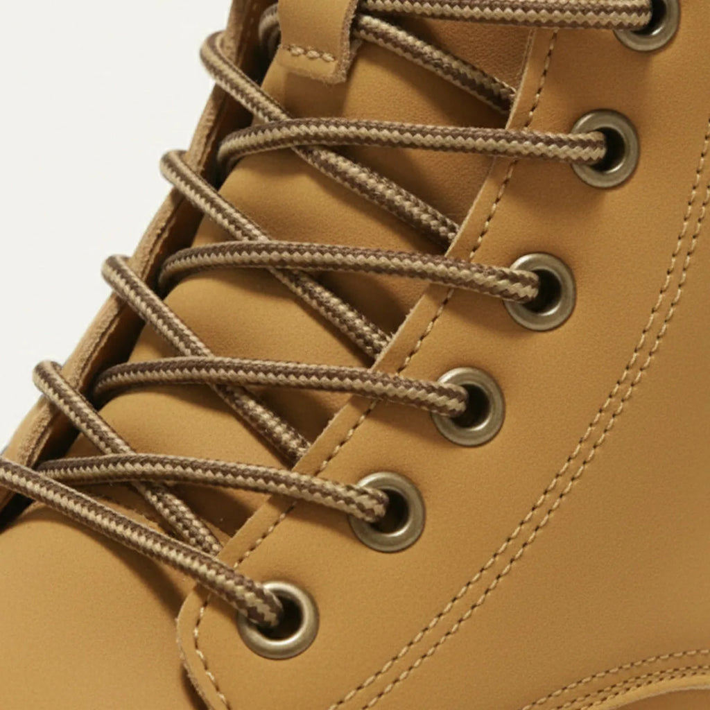 Macro shot of the tonal laces threaded through antique brass eyelets