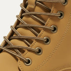 Macro shot of the tonal laces threaded through antique brass eyelets