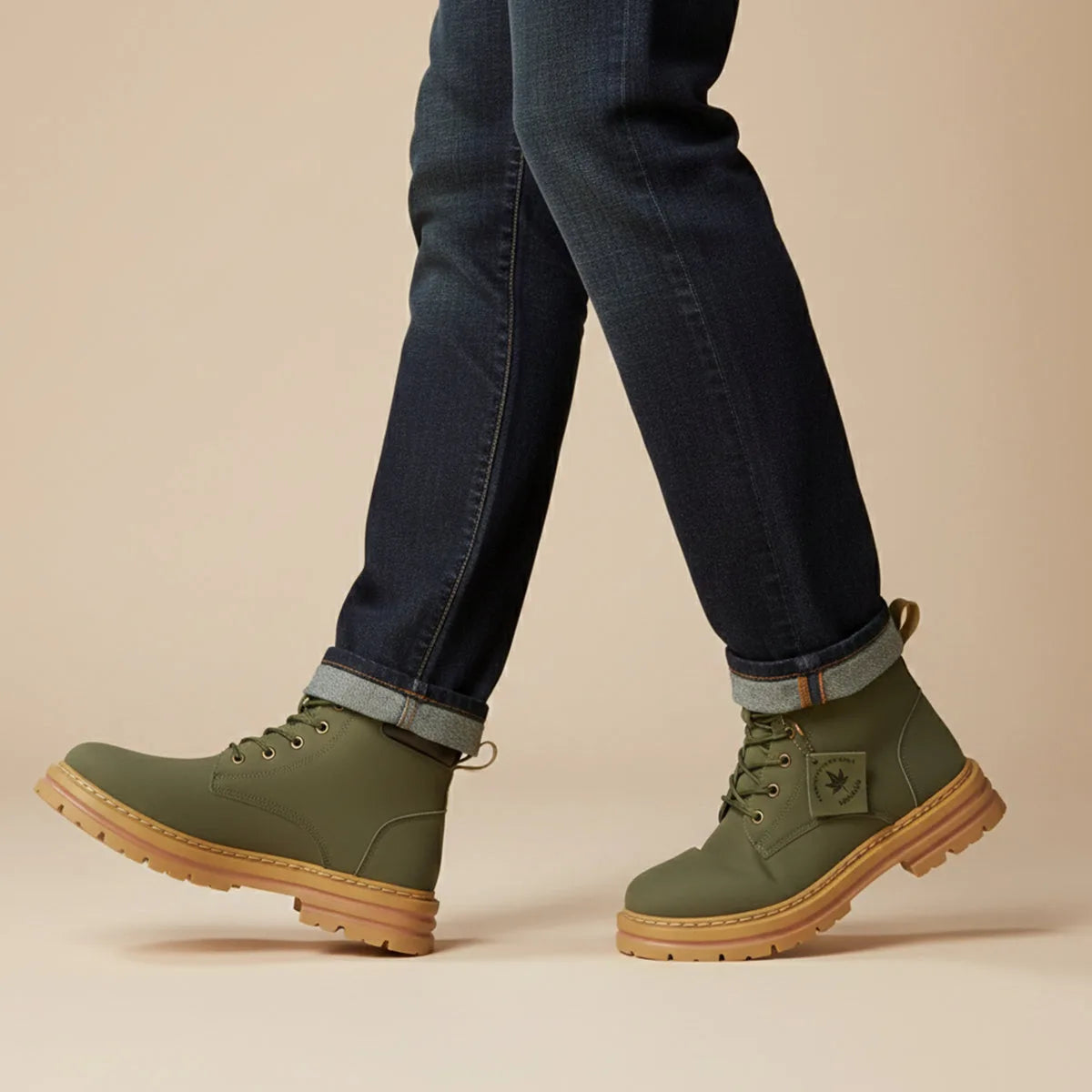 Man walking in khaki green lace-up boots paired with dark denim turn-ups