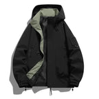 Black hooded jacket laid flat with contrasting sage green inner lining visible through the open front zip