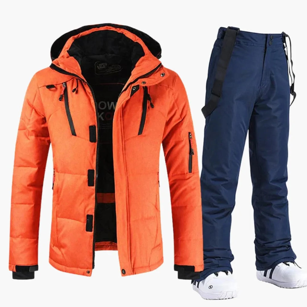 Bright orange hooded ski jacket paired with navy blue bib snow trousers and shoulder straps