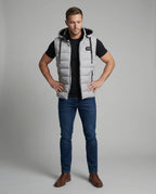 Full-length front view of a man styling a grey quilted gilet with a black t-shirt, jeans and brown boots