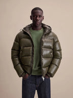 Close-up front view of the olive puffer jacket showing water droplets beading on the high-shine quilted fabric