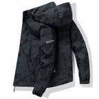 Black camouflage-print hooded jacket folded flat, showing geometric pattern and zip chest pocket detail