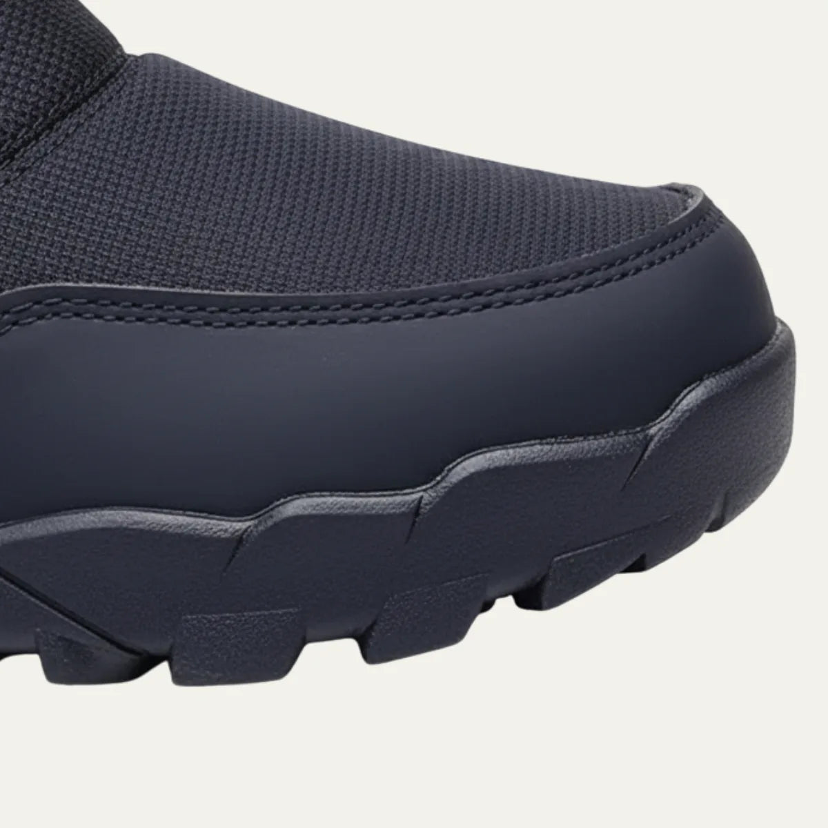 Close-up of the reinforced toe cap and deep-lug rubber outsole of a black snow boot