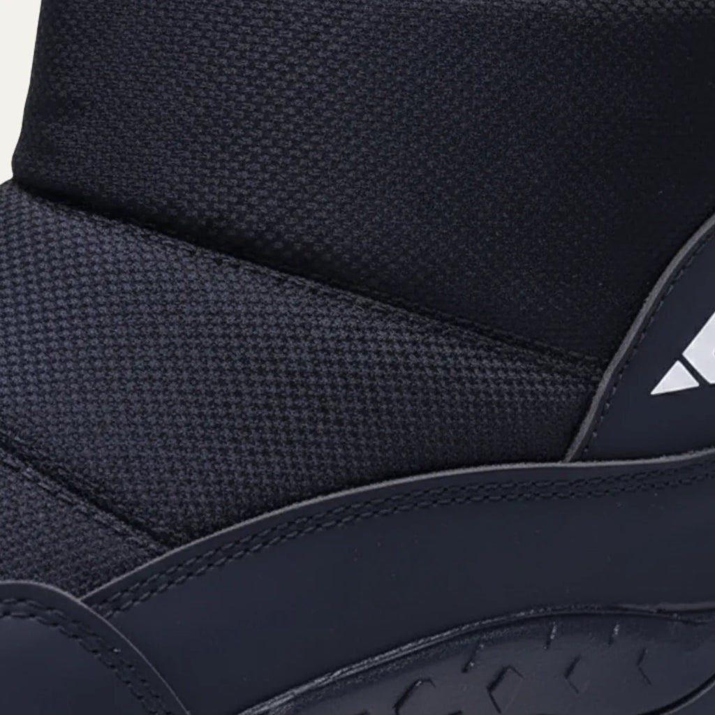 Detail shot of the quilted ankle cuff, textured panel and reflective side logo on a black snow boot