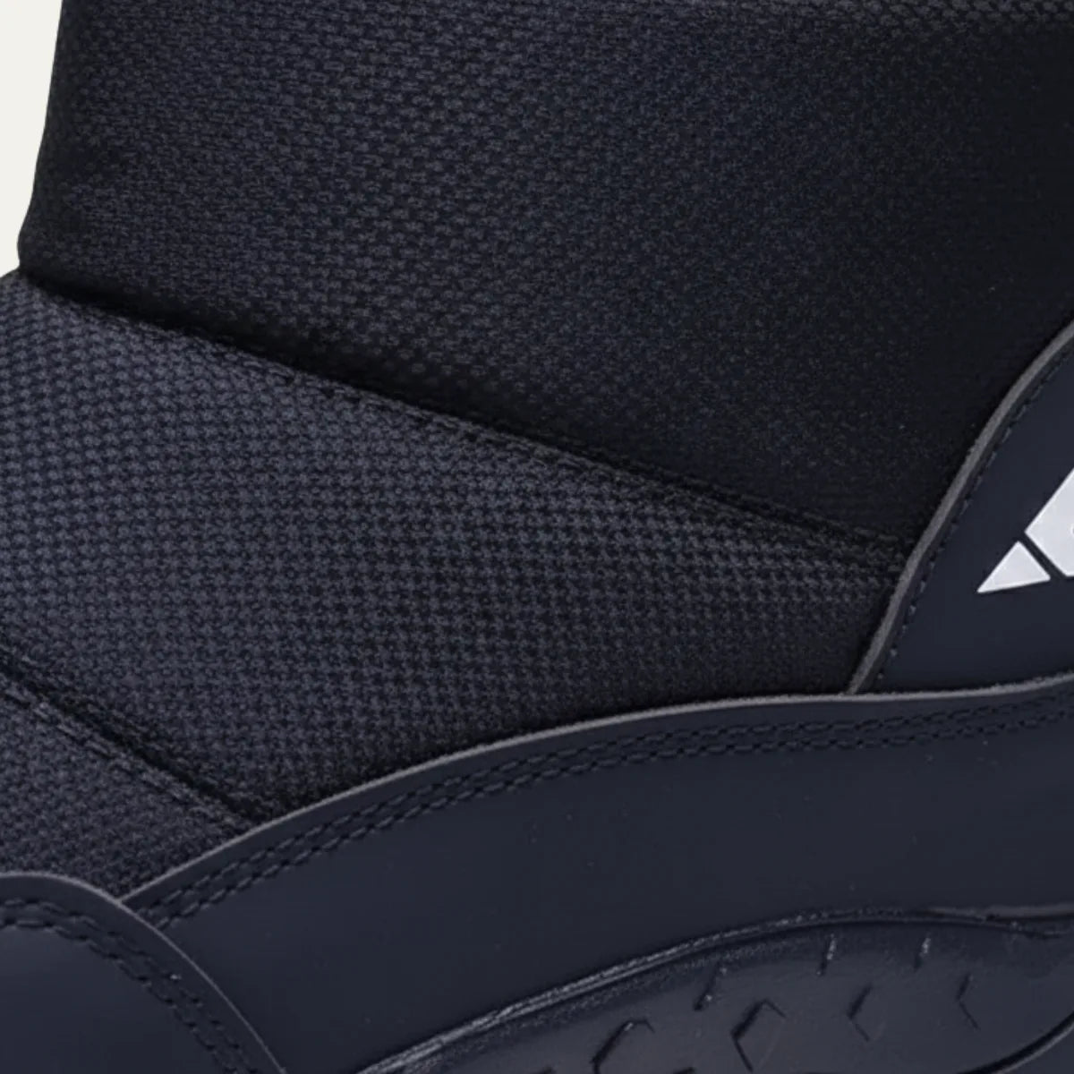 Detail shot of the quilted ankle cuff, textured panel and reflective side logo on a black snow boot