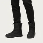 Front view of a person walking in black zip-up snow boots with drawstring ankle cuffs