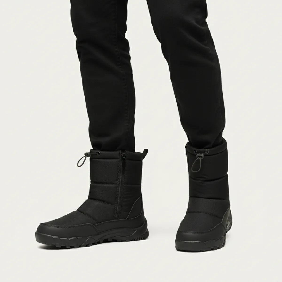 Front view of a person walking in black zip-up snow boots with drawstring ankle cuffs