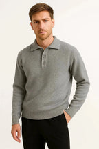 Front view of man wearing a grey heathered knit polo jumper with button collar, styled with black trousers