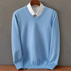 Sky blue V-neck jumper with a layered white shirt collar, shown on a wooden hanger against a grey wall.