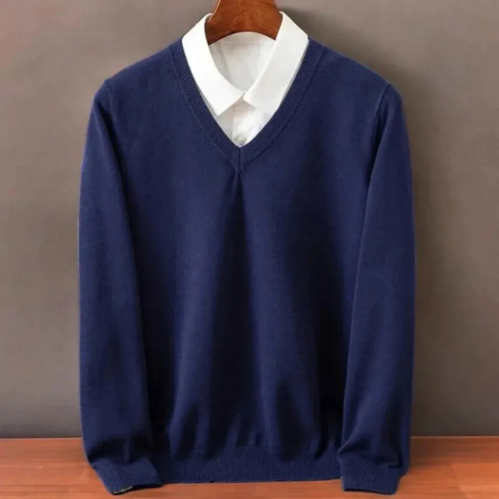 Navy blue V-neck jumper layered over a white shirt collar, close-up of the ribbed trim and long sleeves.