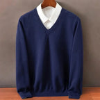 Navy blue V-neck jumper layered over a white shirt collar, close-up of the ribbed trim and long sleeves.