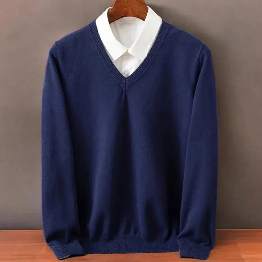 Navy blue V-neck jumper layered over a white shirt collar, close-up of the ribbed trim and long sleeves.