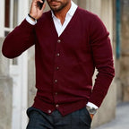 Man on the phone wearing a burgundy knitted cardigan buttoned over a white shirt with checked trousers