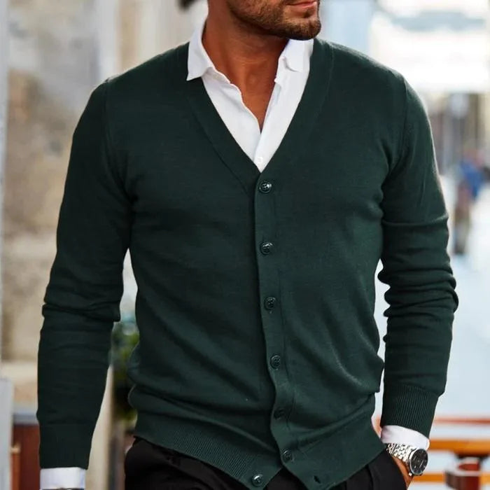 Front view of a dark green knitted cardigan with a V-neck layered over a white collared shirt