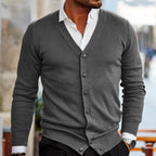 Grey cardigan with ribbed cuffs and a full button placket worn open at the collar over a white shirt