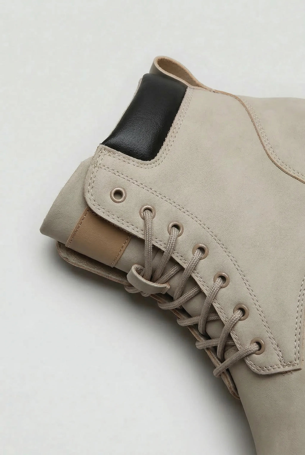 Close-up of the ankle boot's eyelets, laces, pull tab and black and tan heel trim detail