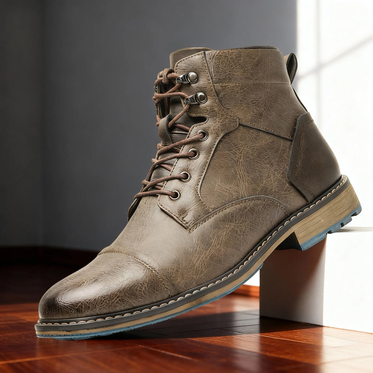 Side profile of stone taupe leather boot with contrasting dark heel panel and blue-accented sole
