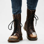 Close-up of brown leather combat boots worn with jeans, laces tied in a bow at the front