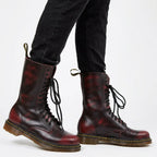Close-up of burgundy red combat boots worn with black trousers, showing lace-up detail