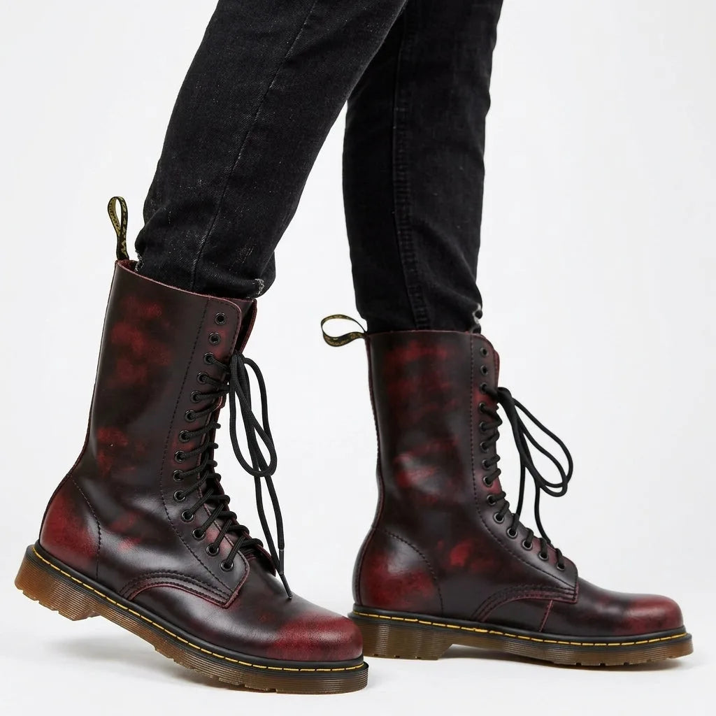 Close-up of burgundy red combat boots worn with black trousers, showing lace-up detail