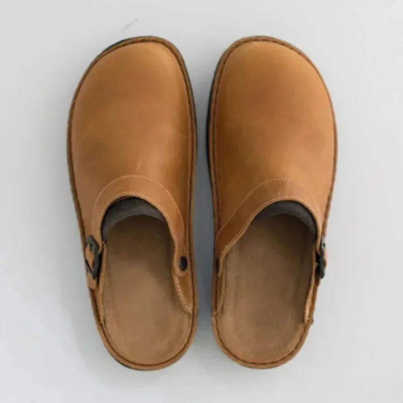 Top-down view of tan leather clog mules showing the rounded toe, stitched edges and buckle fastening