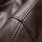 Close-up of brown leather grain and stitched seam detail, showing fine pebbled texture and topstitching