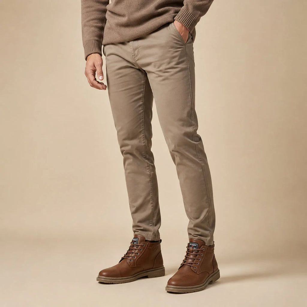 Man in taupe trousers wearing brown lace-up leather ankle boots, side view