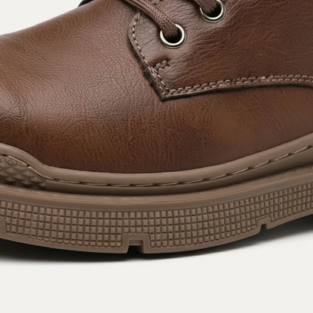Close-up of brown leather toe cap showing stitching detail and textured rubber sole