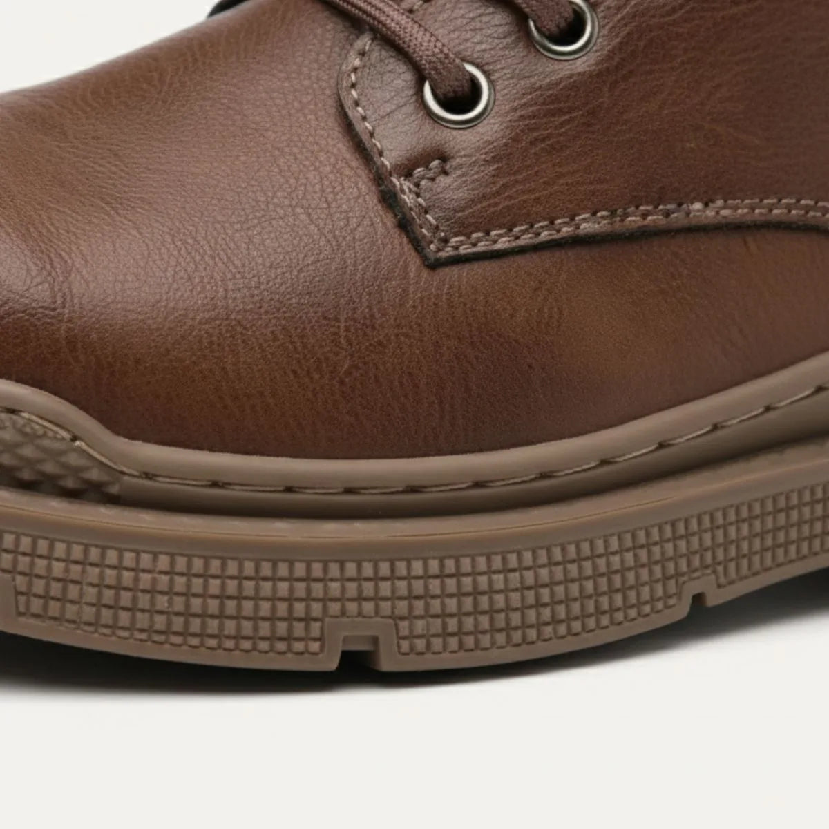 Close-up of brown leather toe cap showing stitching detail and textured rubber sole