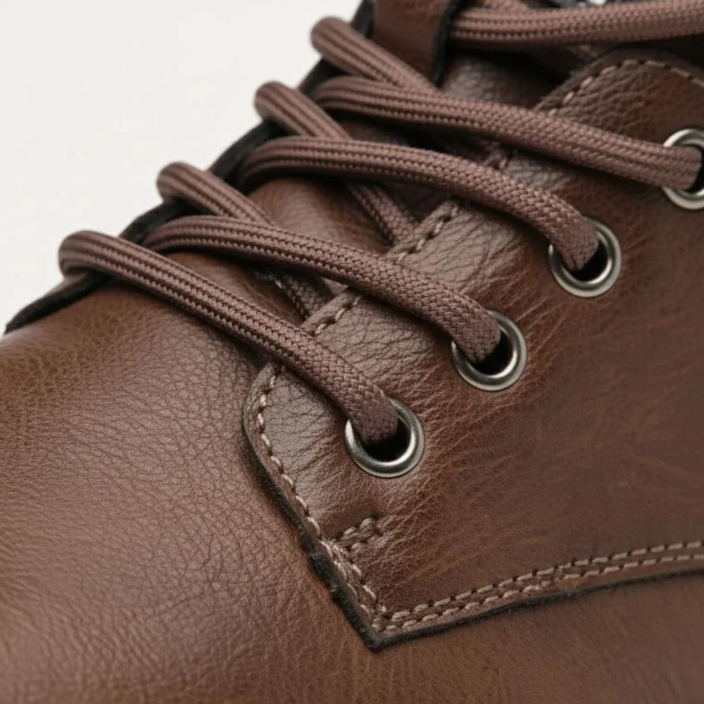 Macro shot of brown laces threaded through metal eyelets on leather upper