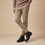 Man in taupe trousers wearing black lace-up leather ankle boots, side view