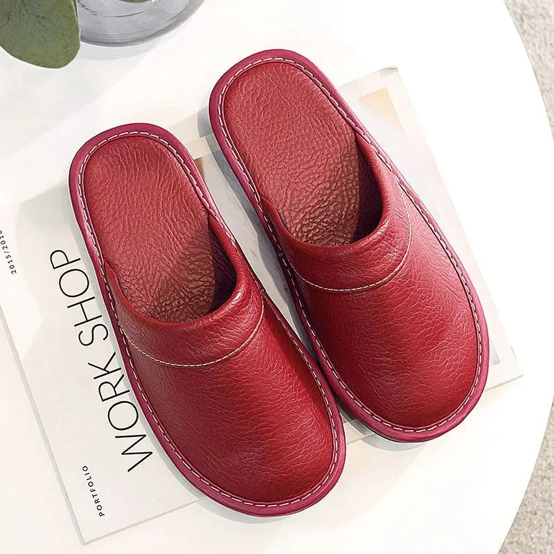Angled view of brown leather slippers worn with grey trousers, showing the backless mule cut from above