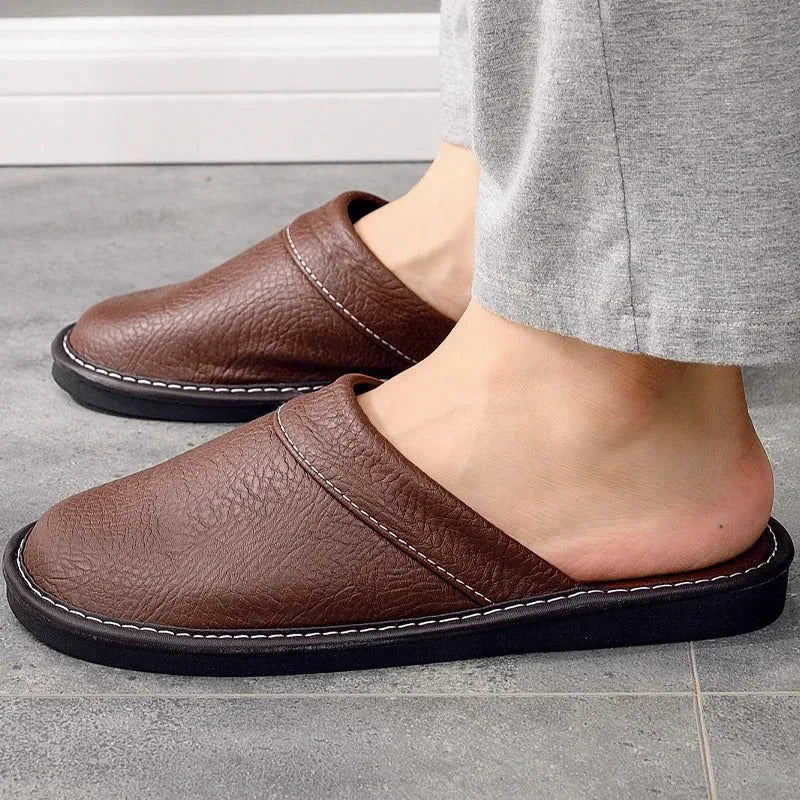 Side view of brown leather slipper worn with grey trousers, showing low-top slip-on design and black sole