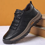 Side view of a black leather shoe styled against an orange backdrop with stacked books