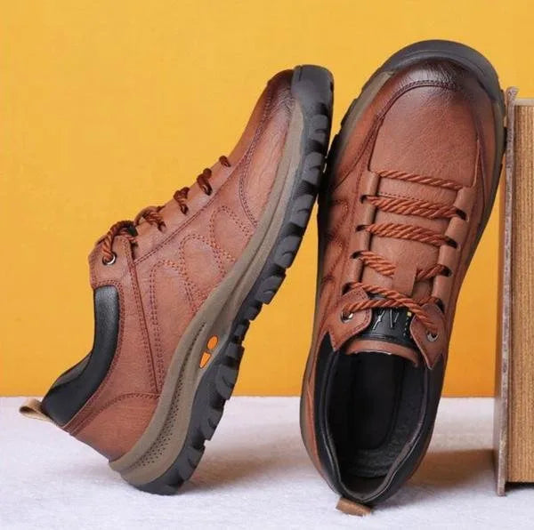 Pair of brown leather shoes displayed together against an orange backdrop with stacked books