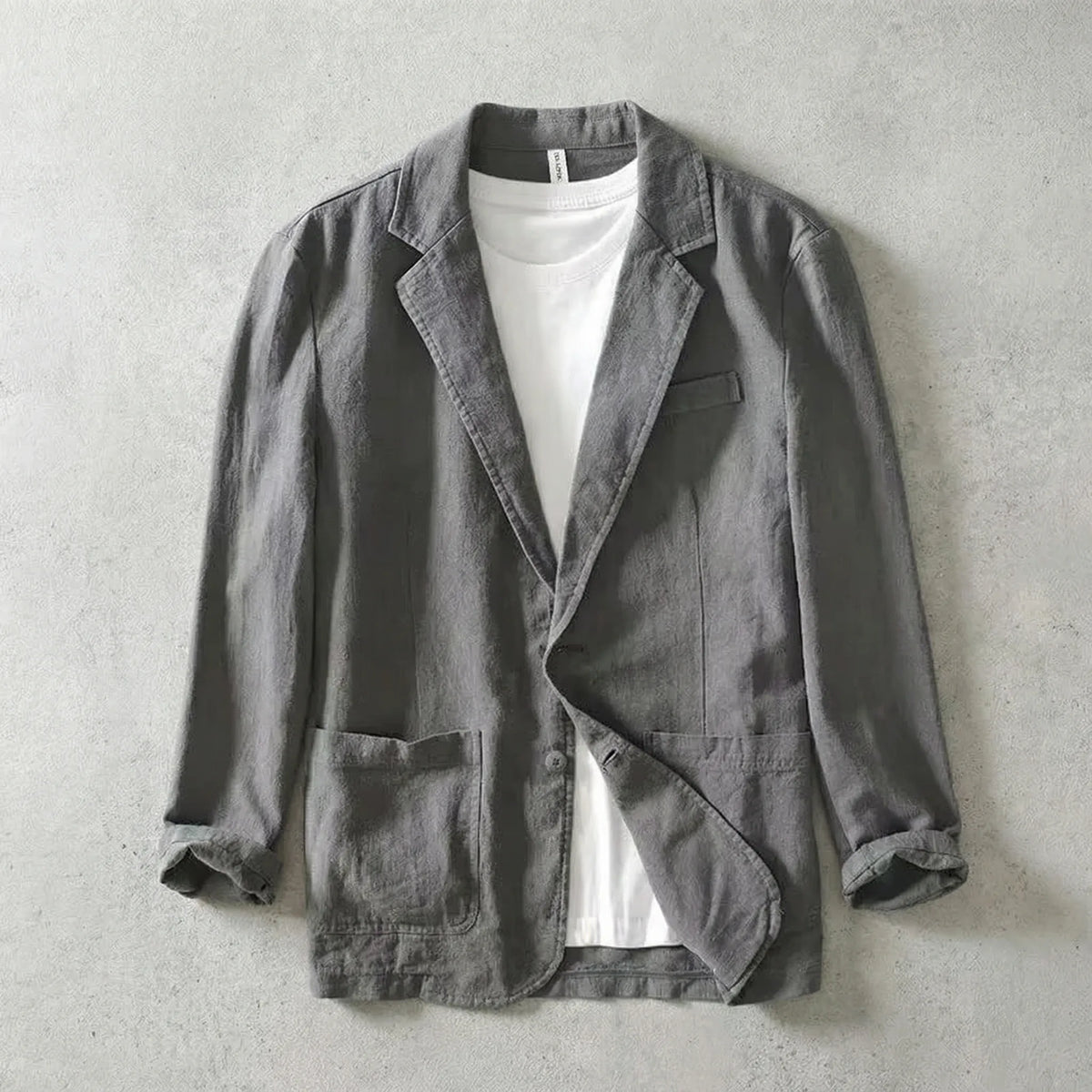Grey linen-blend blazer worn open over a white t-shirt, showing notch lapels and chest pocket detail