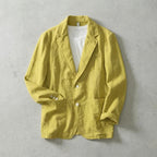 Mustard yellow linen jacket buttoned over a white t-shirt, showing pearl buttons and rolled cuffs