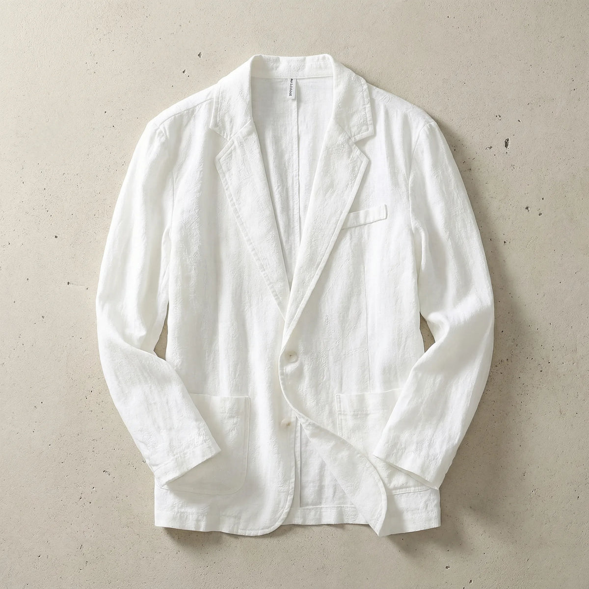 White textured linen blazer laid flat, showing notch lapel, chest welt pocket and patch pockets