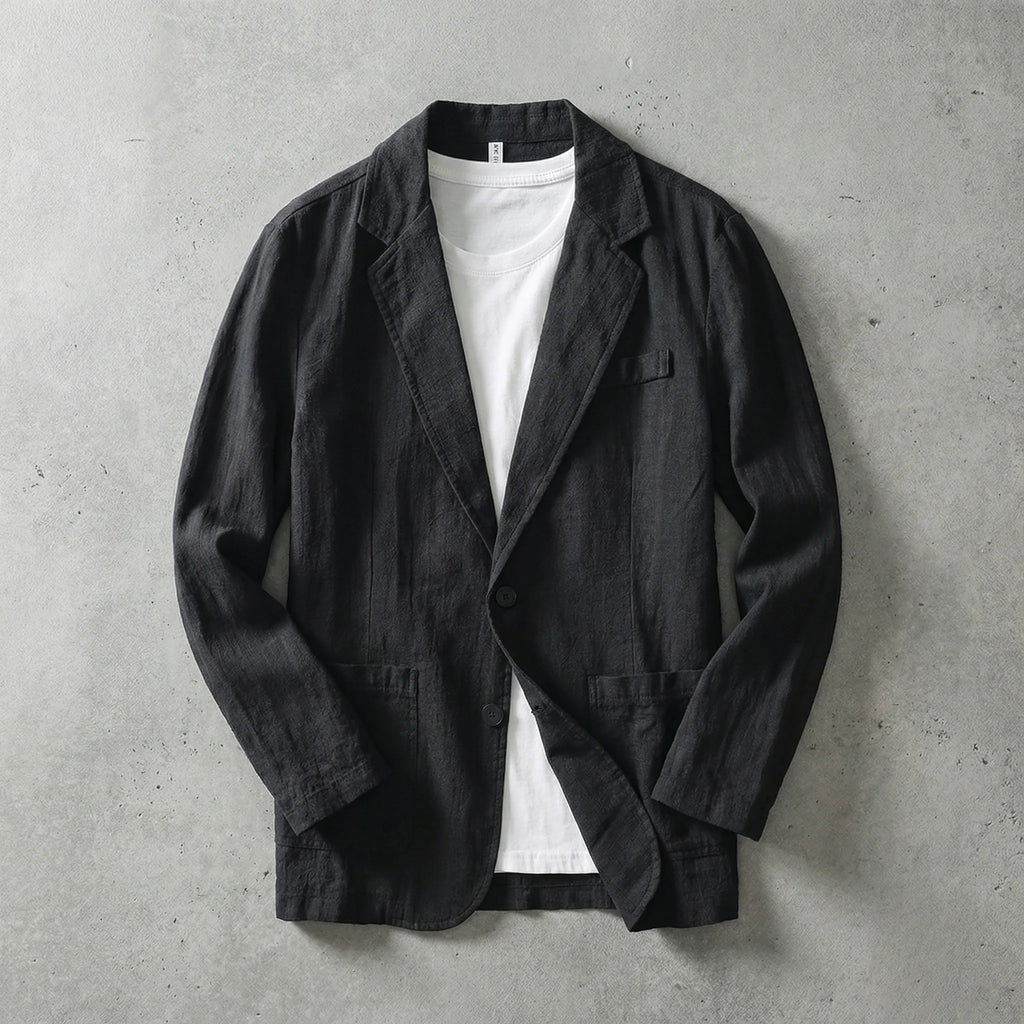 Black linen blazer laid flat buttoned over a white t-shirt, showing clean lapel and twin patch pockets