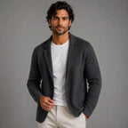 Man wearing a grey knitted blazer cardigan buttoned at the waist, standing against a plain studio background